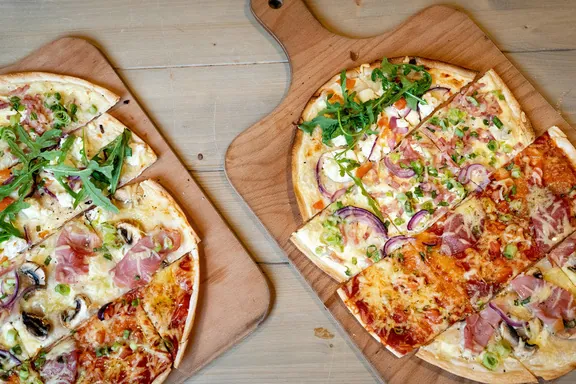 Zwei frisch belegte Pizzen auf Holzbrettern